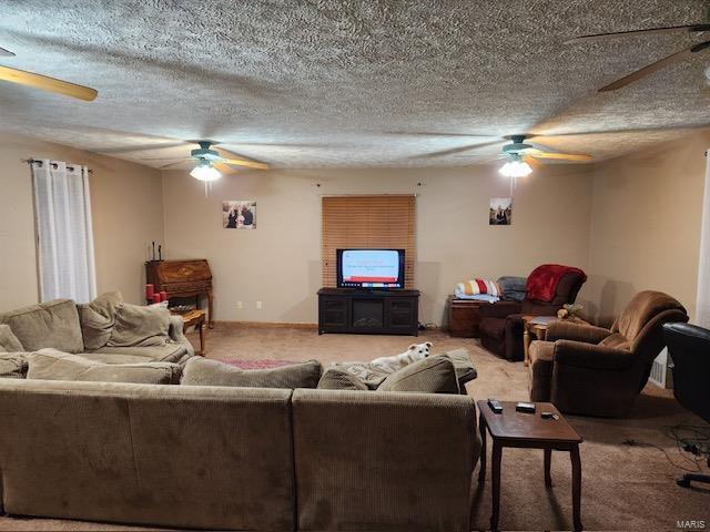 living room featuring a textured ceiling, ceiling fan, and carpet