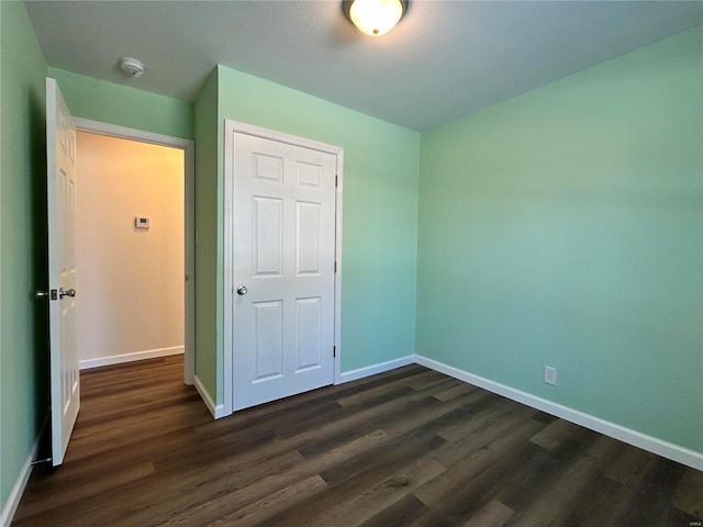 unfurnished bedroom with dark wood-style floors and baseboards