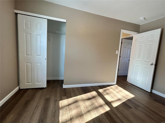 unfurnished bedroom with a closet, baseboards, and wood finished floors