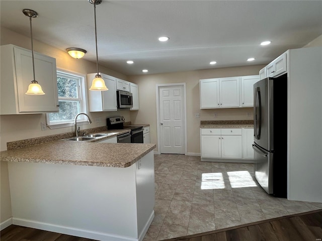 kitchen featuring appliances with stainless steel finishes, white cabinets, a sink, and a peninsula