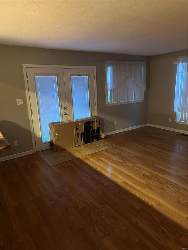 unfurnished living room featuring hardwood / wood-style floors, a textured ceiling, and french doors