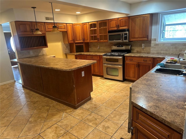 kitchen with appliances with stainless steel finishes, decorative light fixtures, sink, backsplash, and light tile patterned flooring