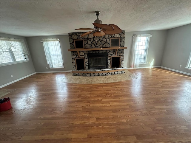 unfurnished living room featuring hardwood / wood-style flooring, a textured ceiling, ceiling fan, and a fireplace