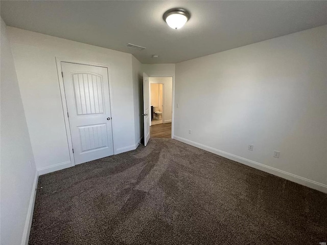 unfurnished bedroom featuring a closet and dark colored carpet