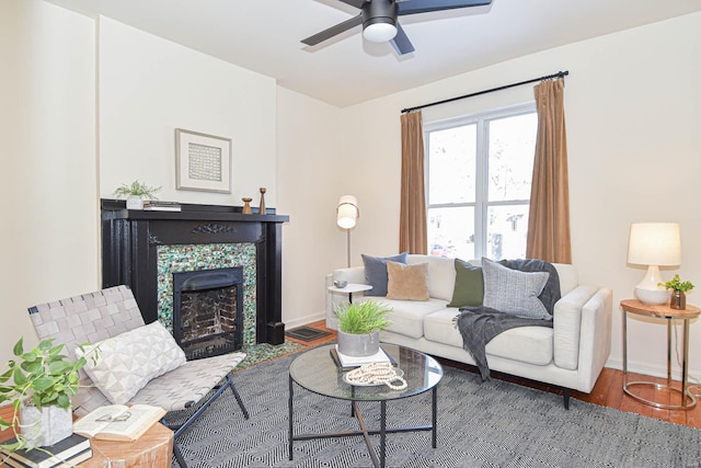 living room with wood-type flooring, a tile fireplace, and ceiling fan