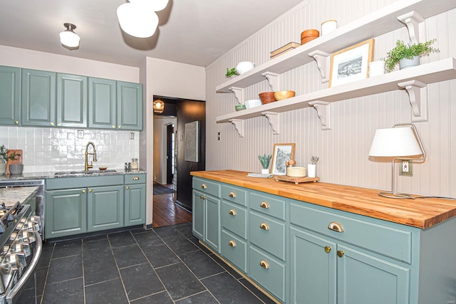 kitchen featuring gas stove, sink, wood counters, and decorative backsplash