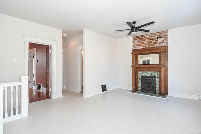 unfurnished living room with a large fireplace, ceiling fan, and light wood-type flooring