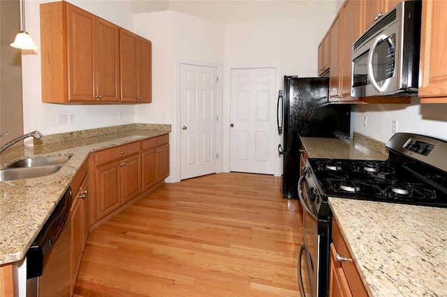 kitchen with sink, light hardwood / wood-style flooring, pendant lighting, stainless steel appliances, and light stone countertops