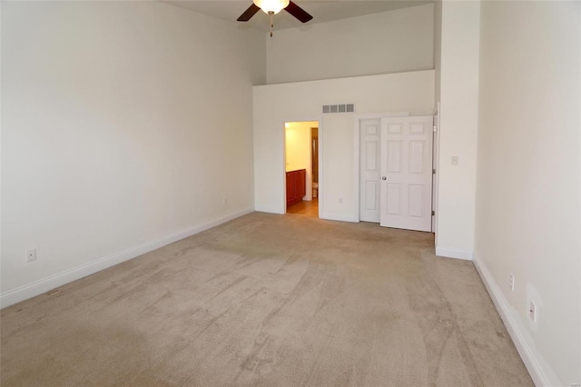 unfurnished bedroom featuring high vaulted ceiling, ensuite bath, light colored carpet, and ceiling fan