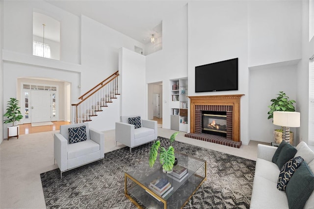 living area featuring a brick fireplace, carpet, a high ceiling, and stairway