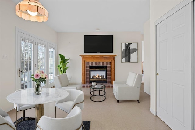 living area featuring a brick fireplace and baseboards