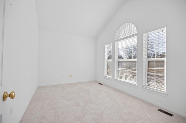 carpeted empty room featuring lofted ceiling, visible vents, and baseboards