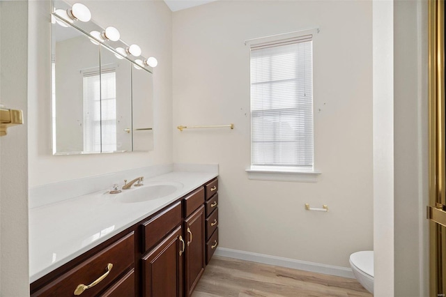 bathroom with baseboards, vanity, toilet, and wood finished floors