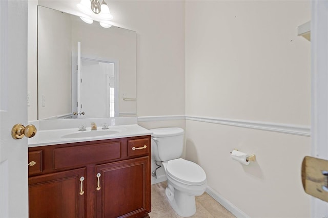 bathroom with tile patterned flooring, baseboards, vanity, and toilet