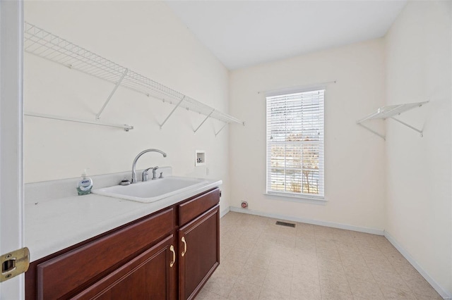 laundry area with washer hookup, a sink, cabinet space, and baseboards