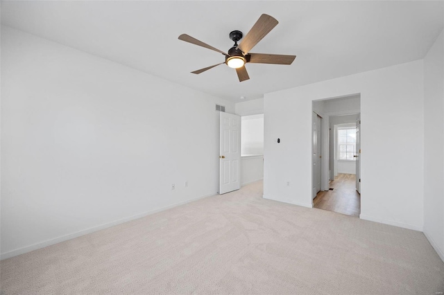 unfurnished bedroom featuring baseboards, ceiling fan, visible vents, and light colored carpet