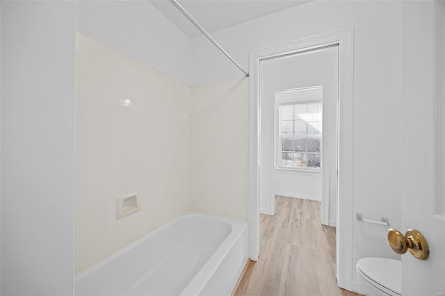 bathroom featuring shower / washtub combination, baseboards, toilet, and wood finished floors