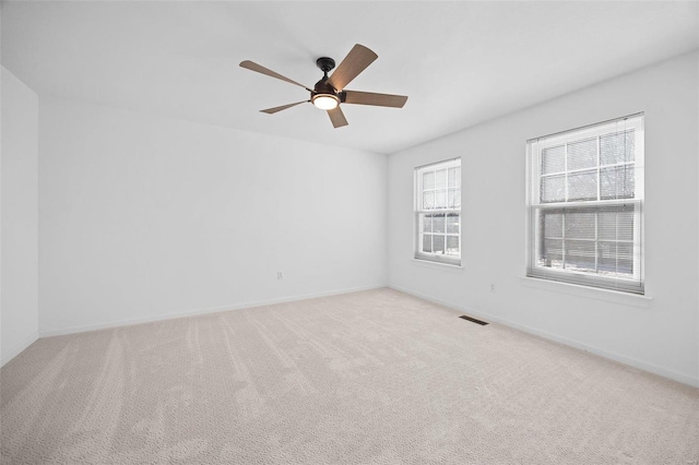 carpeted empty room featuring a ceiling fan, visible vents, and baseboards