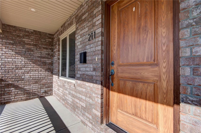 entrance to property with covered porch and brick siding