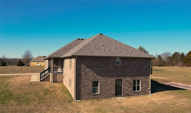 view of property exterior with a shingled roof, brick siding, and a yard