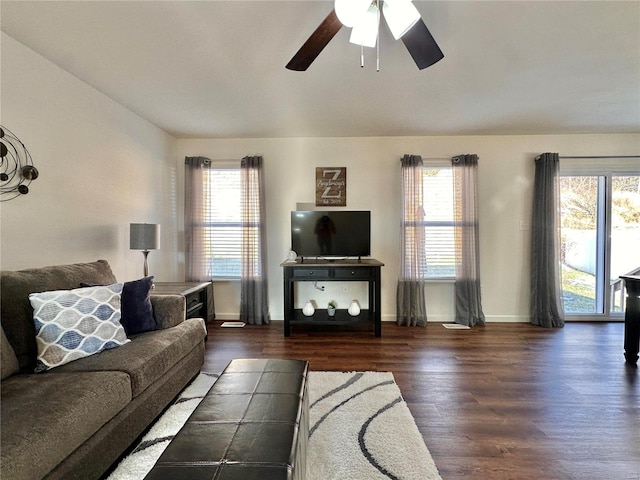 living room featuring dark wood-type flooring and ceiling fan