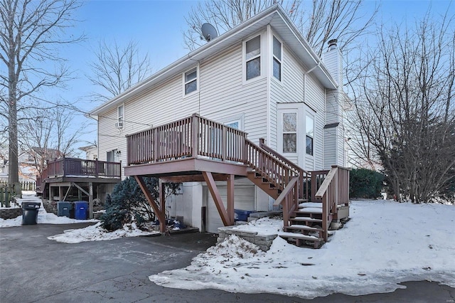 snow covered back of property with a deck