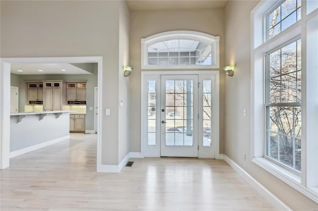 entryway with a towering ceiling and light hardwood / wood-style floors