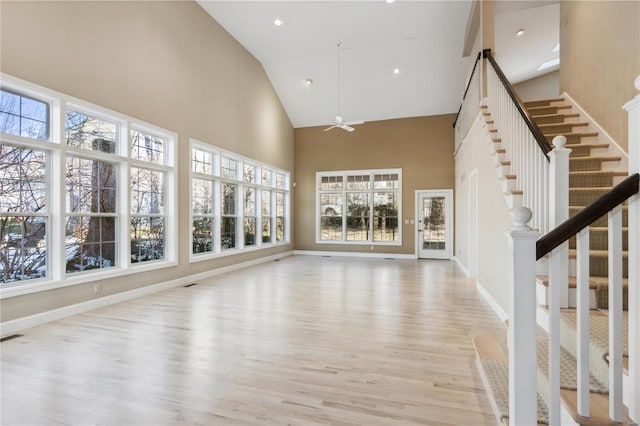 unfurnished living room featuring ceiling fan, high vaulted ceiling, a healthy amount of sunlight, and light hardwood / wood-style floors