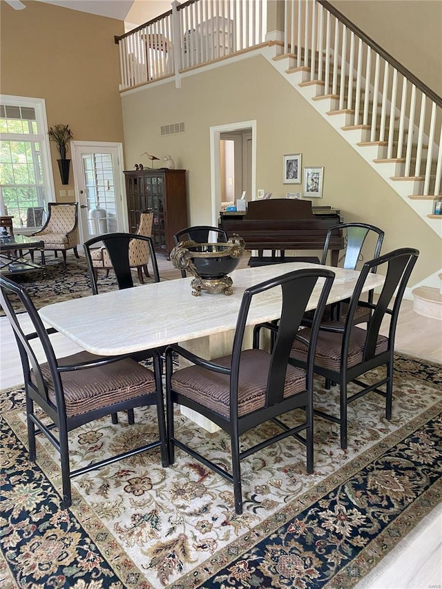 dining area featuring a towering ceiling and wood-type flooring