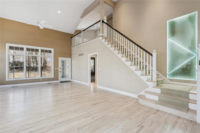 unfurnished living room featuring ceiling fan, a high ceiling, and light wood-type flooring