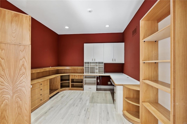 kitchen featuring white cabinetry, built in desk, and light hardwood / wood-style flooring