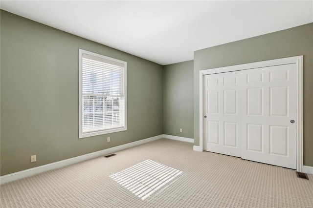 unfurnished bedroom with light colored carpet and a closet