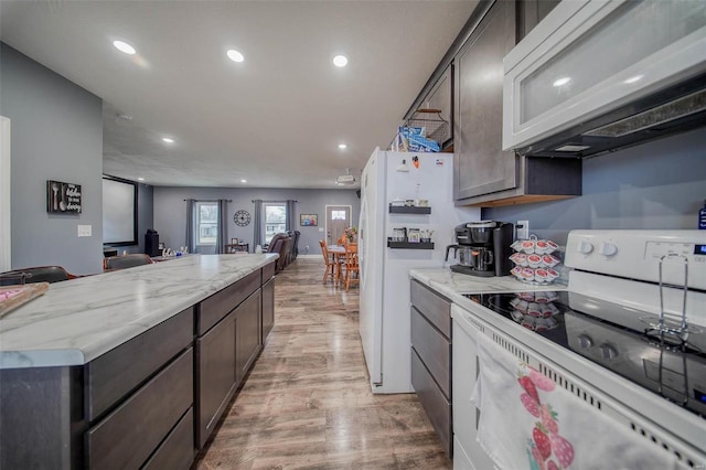 kitchen with extractor fan, dark brown cabinetry, light stone countertops, white appliances, and light hardwood / wood-style flooring