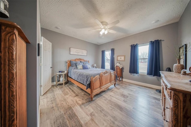 bedroom featuring ceiling fan, a textured ceiling, and light hardwood / wood-style floors