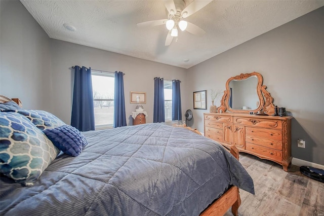 bedroom featuring ceiling fan, a textured ceiling, and light wood-type flooring