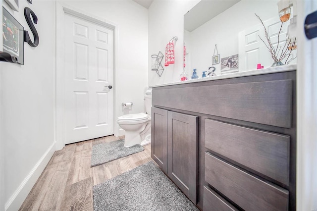 bathroom with hardwood / wood-style flooring, vanity, and toilet