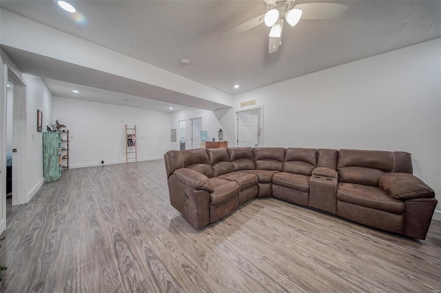 living room with ceiling fan, a textured ceiling, and light hardwood / wood-style flooring