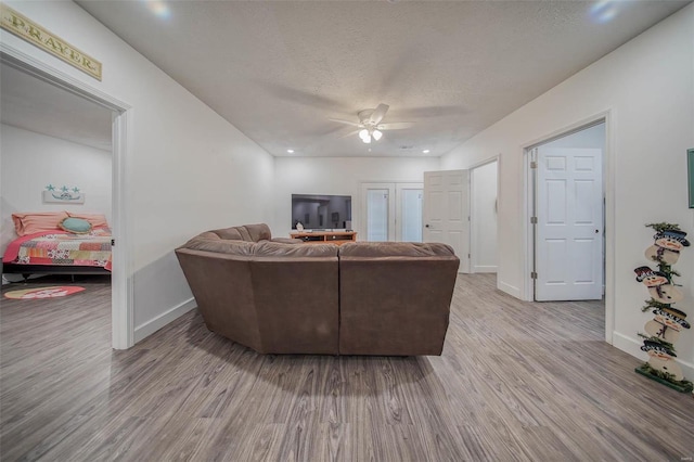 living room with ceiling fan, wood-type flooring, and a textured ceiling