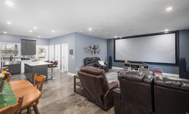 home theater room with recessed lighting, a sink, baseboards, and wood finished floors