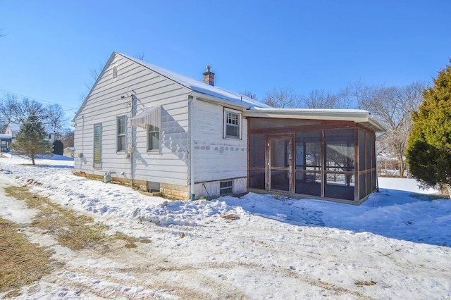 snow covered property featuring a sunroom