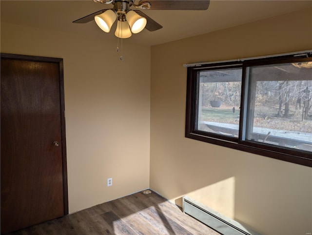 unfurnished bedroom with ceiling fan, a baseboard radiator, and hardwood / wood-style floors