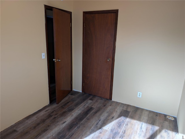 unfurnished bedroom with dark wood-type flooring and a closet