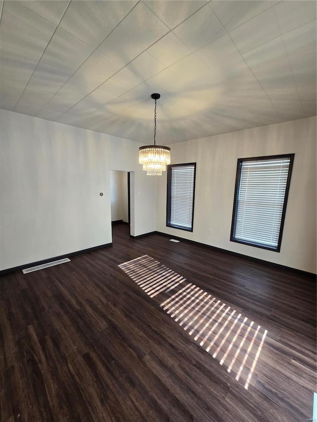 unfurnished room with dark hardwood / wood-style flooring and a notable chandelier