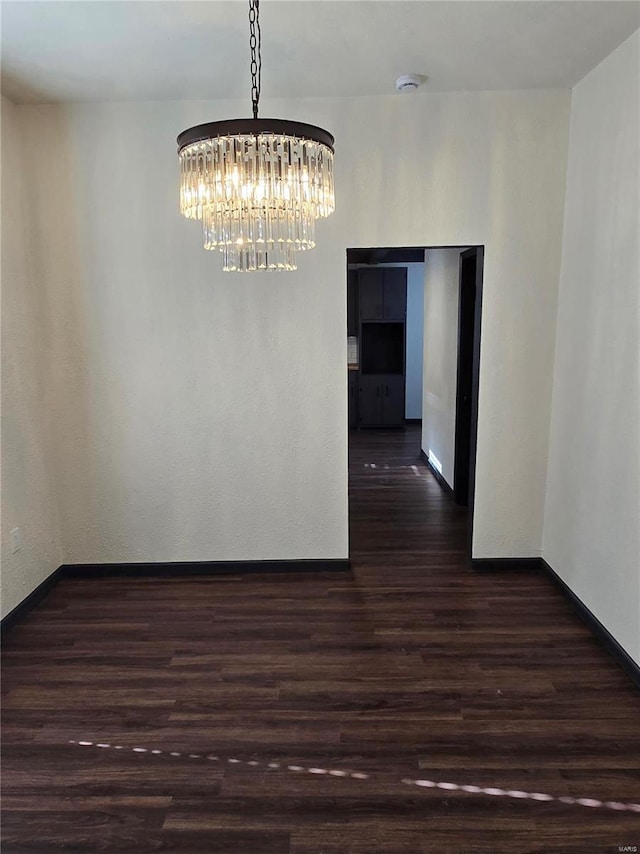 unfurnished dining area with dark hardwood / wood-style flooring and a chandelier