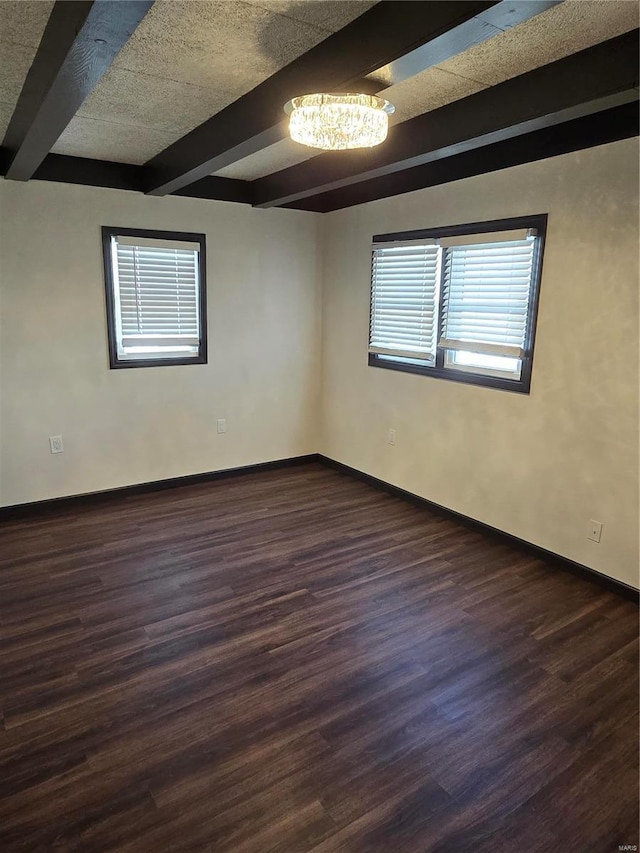 spare room featuring beamed ceiling and dark hardwood / wood-style floors