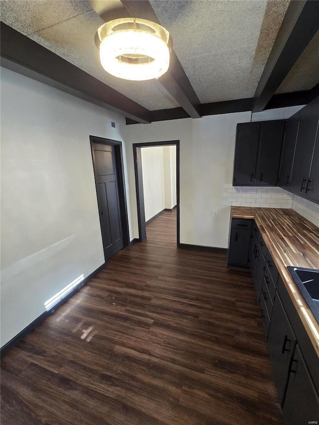 kitchen featuring beamed ceiling, sink, backsplash, wooden counters, and dark hardwood / wood-style flooring