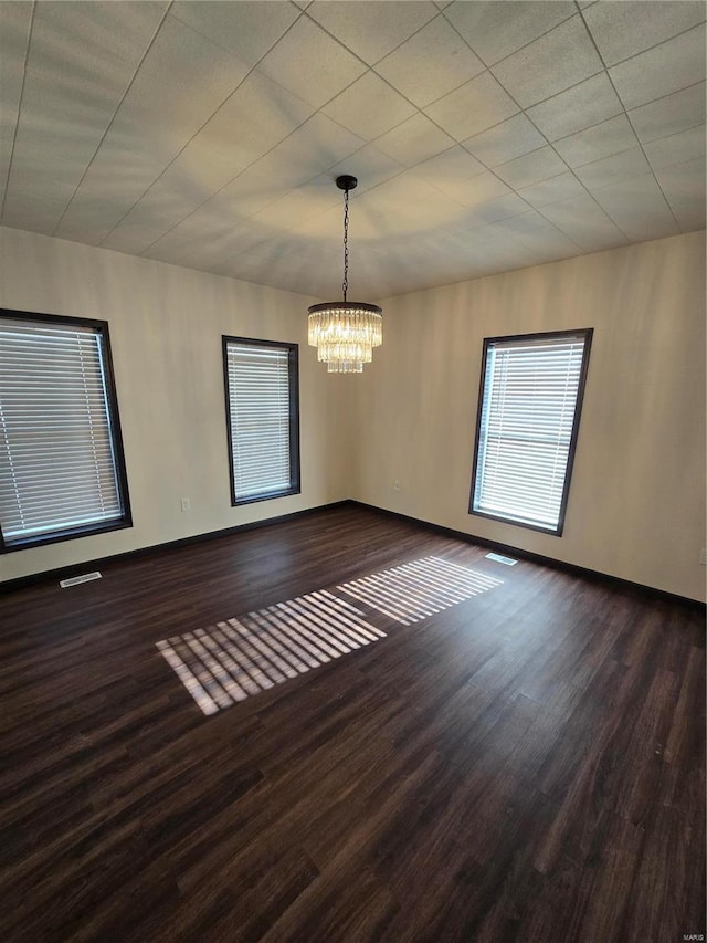 empty room featuring dark hardwood / wood-style flooring and an inviting chandelier