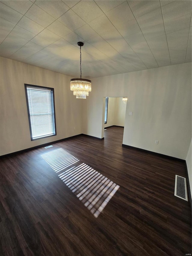 spare room featuring dark hardwood / wood-style floors and a chandelier