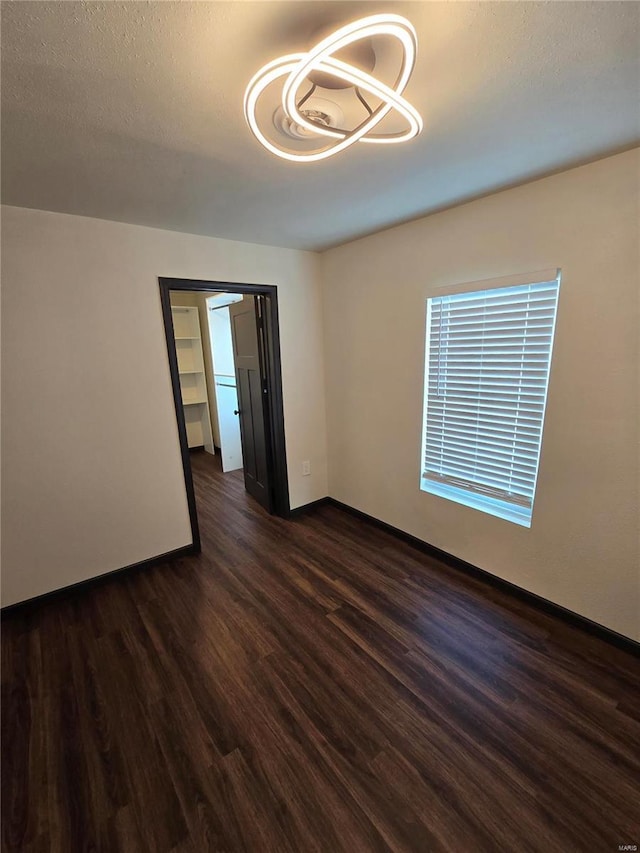 unfurnished room featuring dark wood-type flooring and a textured ceiling