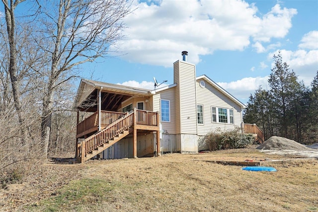 rear view of house featuring a wooden deck and a lawn